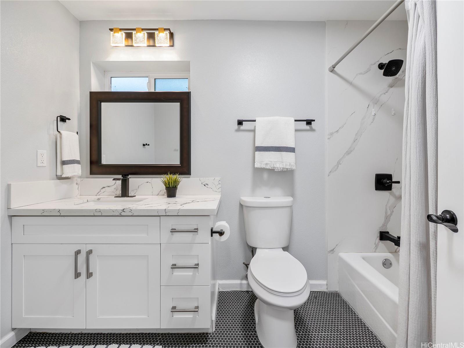 Full bathroom with marble shower surround and quartz vanity